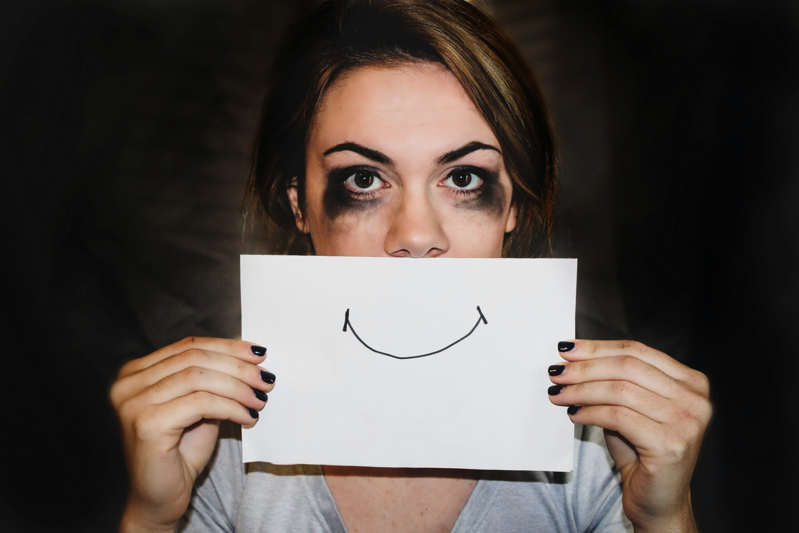 A woman experiencing burnout, hiding her pain with a pretend smile